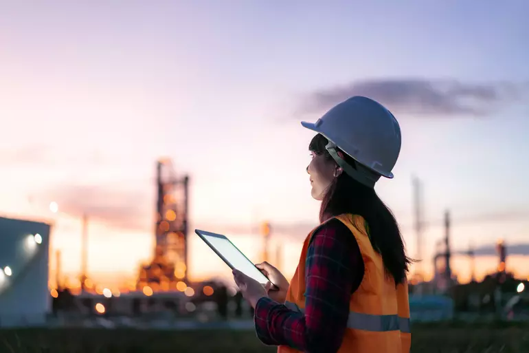 Woman with a tablet computer standing at an industry site.